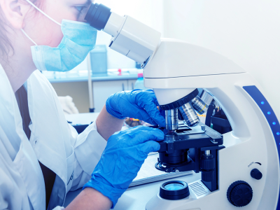 Young female doctor analyzing a biopsy sample at a microscope